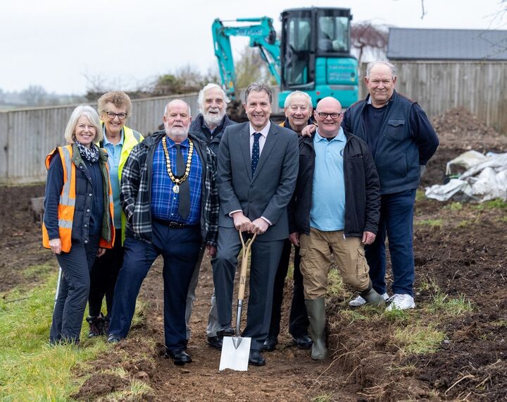 The Metro Mayor Dan Norris standing alongside six members of Radstock Town Council in a dug up grassed area with a digger in the background.