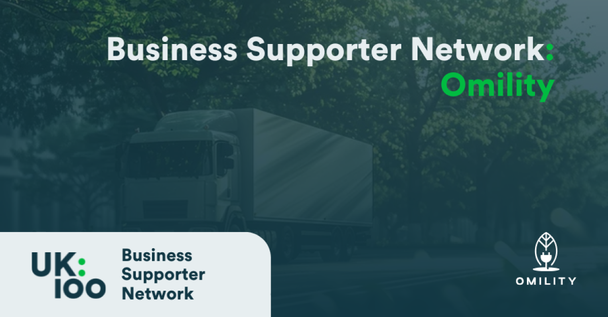 A promotional banner featuring the Business Supporter Network heading in white text overlaid on a dark, blurred background image of a lorry on a tree-lined road. The banner includes two logos: the UK100 Business Supporter Network logo on the left, showing 'UK:100' in a modern design, and the Omility logo on the right, depicting a stylised figure or plant-like symbol in white. The word 'Omility' appears in bright green in the top right corner of the banner. The overall colour scheme's dark blue-green in tone
